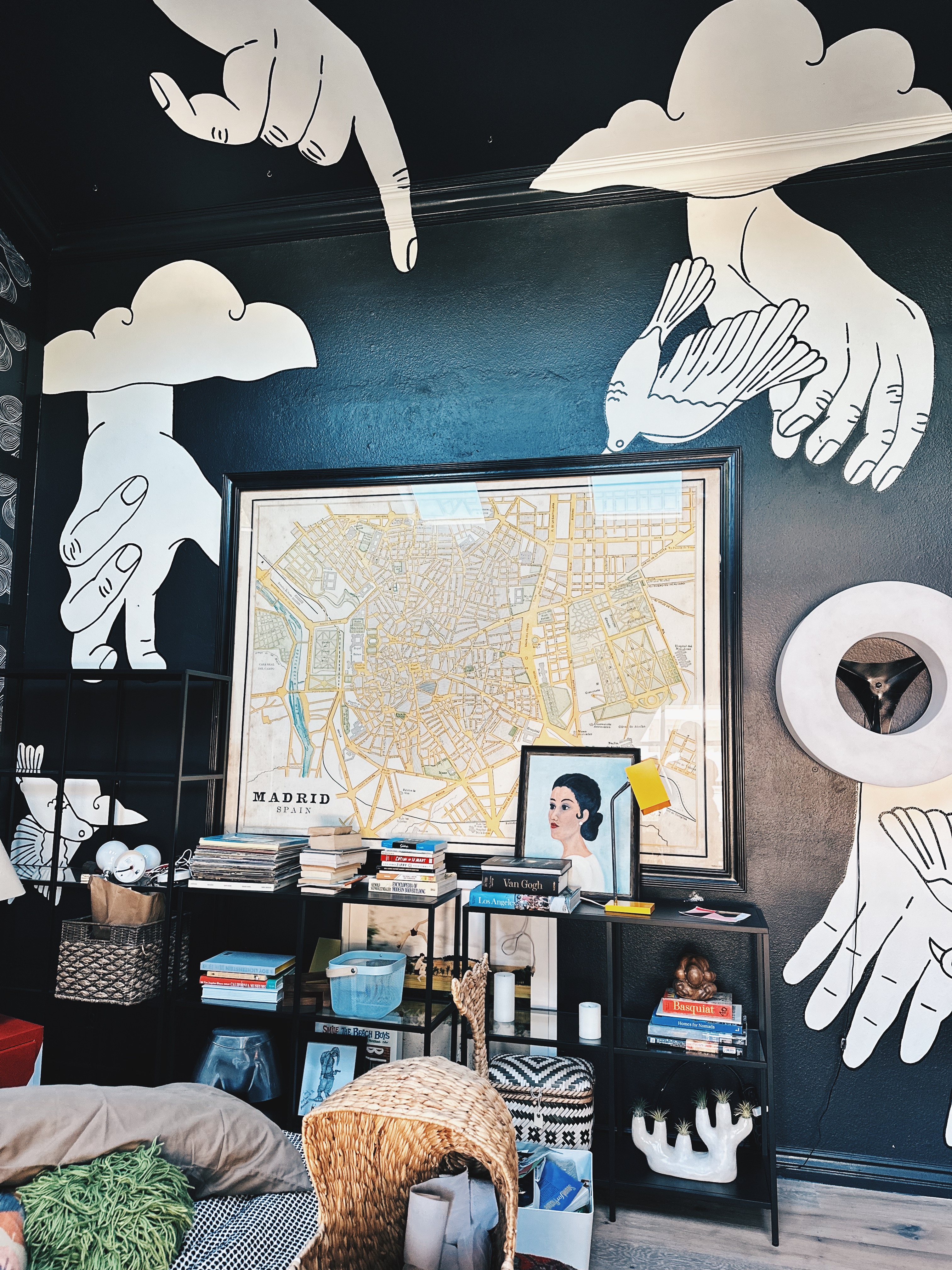 Black bedroom mural with large white hands, clouds and birds painted by a Los Angeles muralist