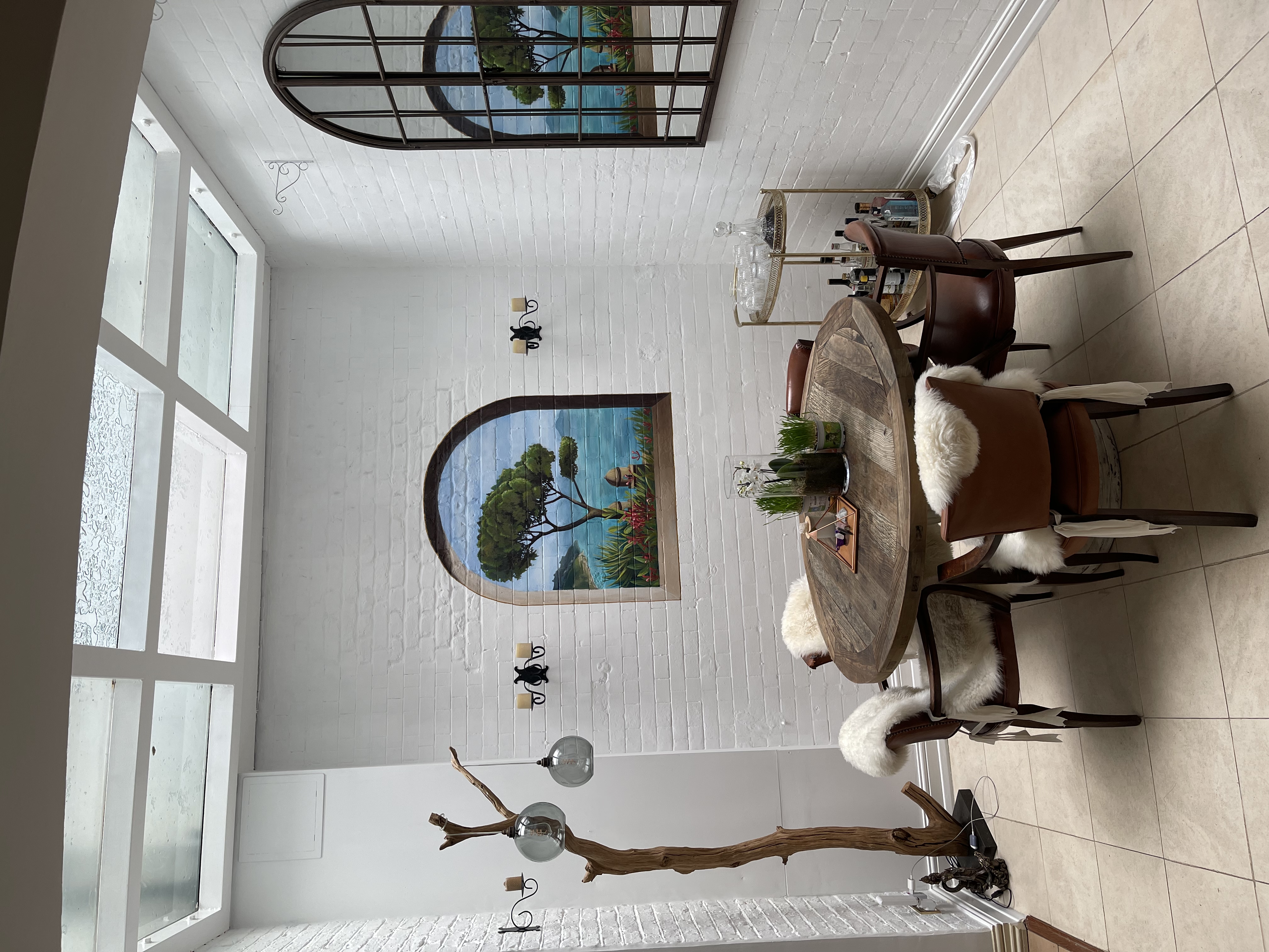Trompe-l'œil arched window mural of a Tuscan landscape painted in a London dining room