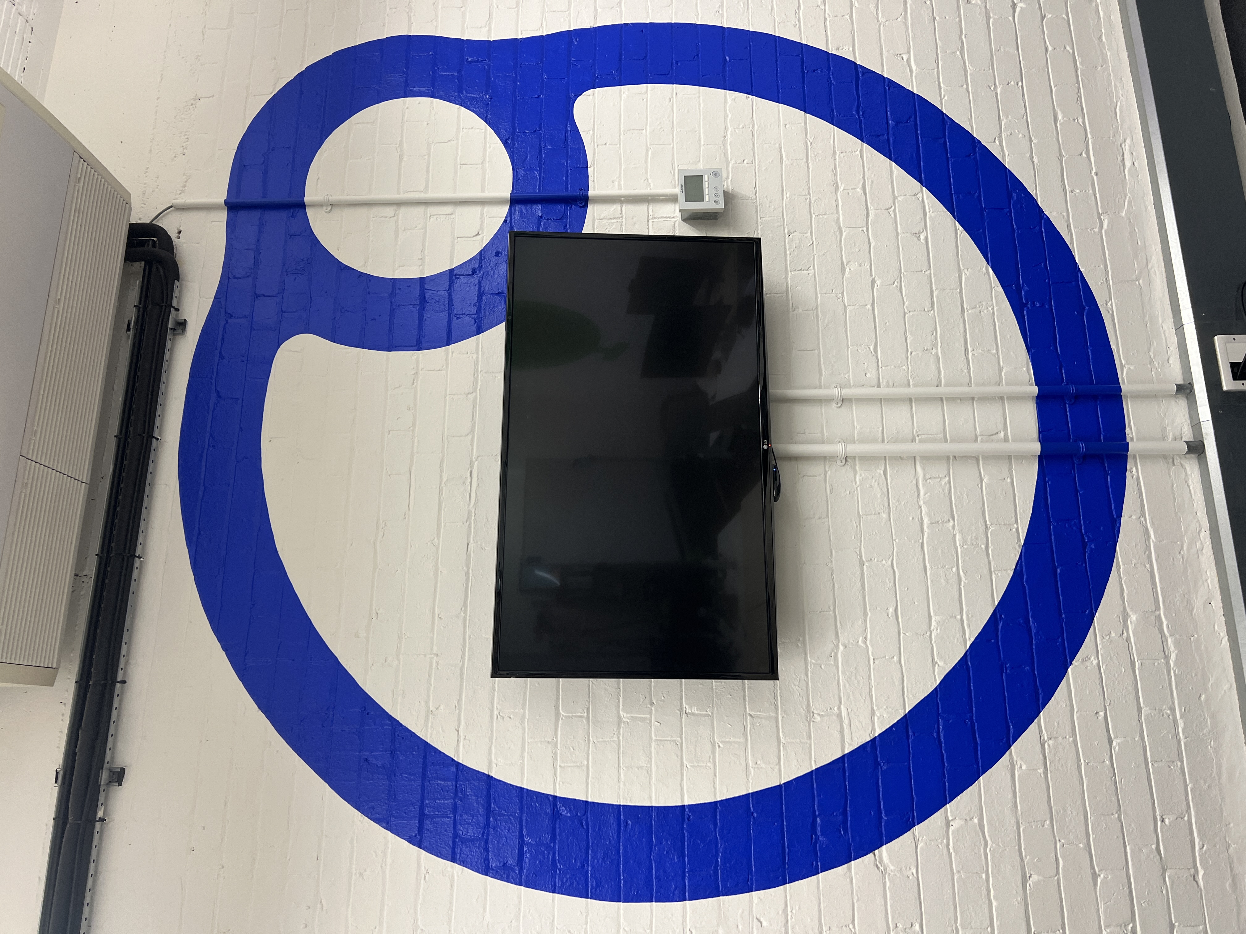 Blue graphic AI-themed mural with binary code, a car and a chessboard, painted in a London tech office