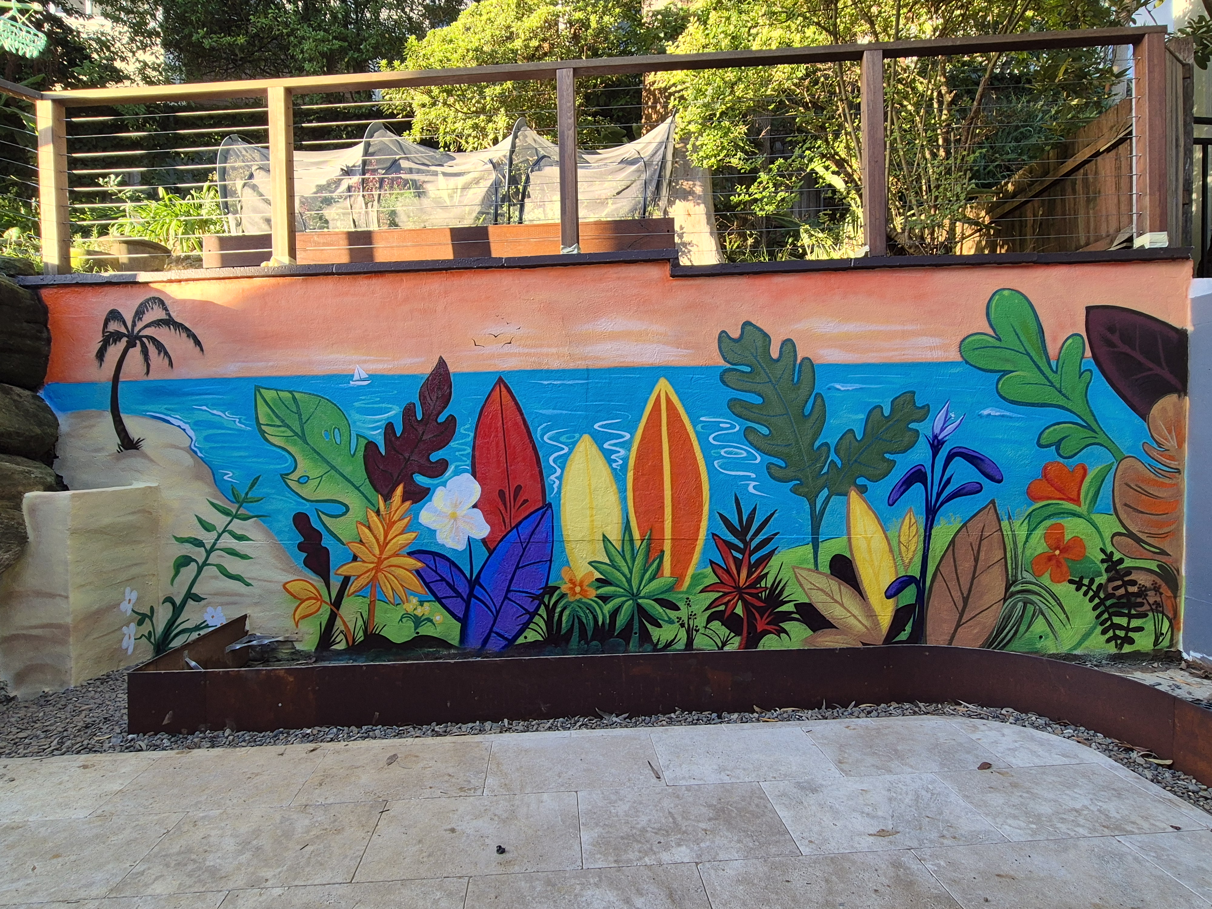 Tropical courtyard mural with surfboards and palm leaves painted on a bagged-cement wall in Mosman, Sydney